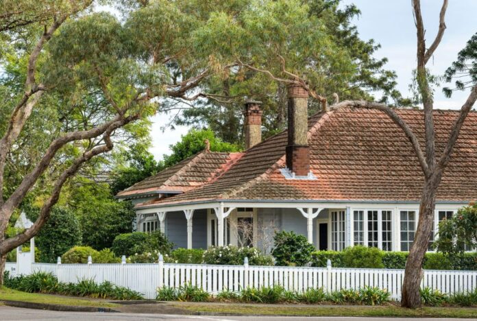 A heritage Newcastle family home behind a white picket fence on a leafy, tree-lined street