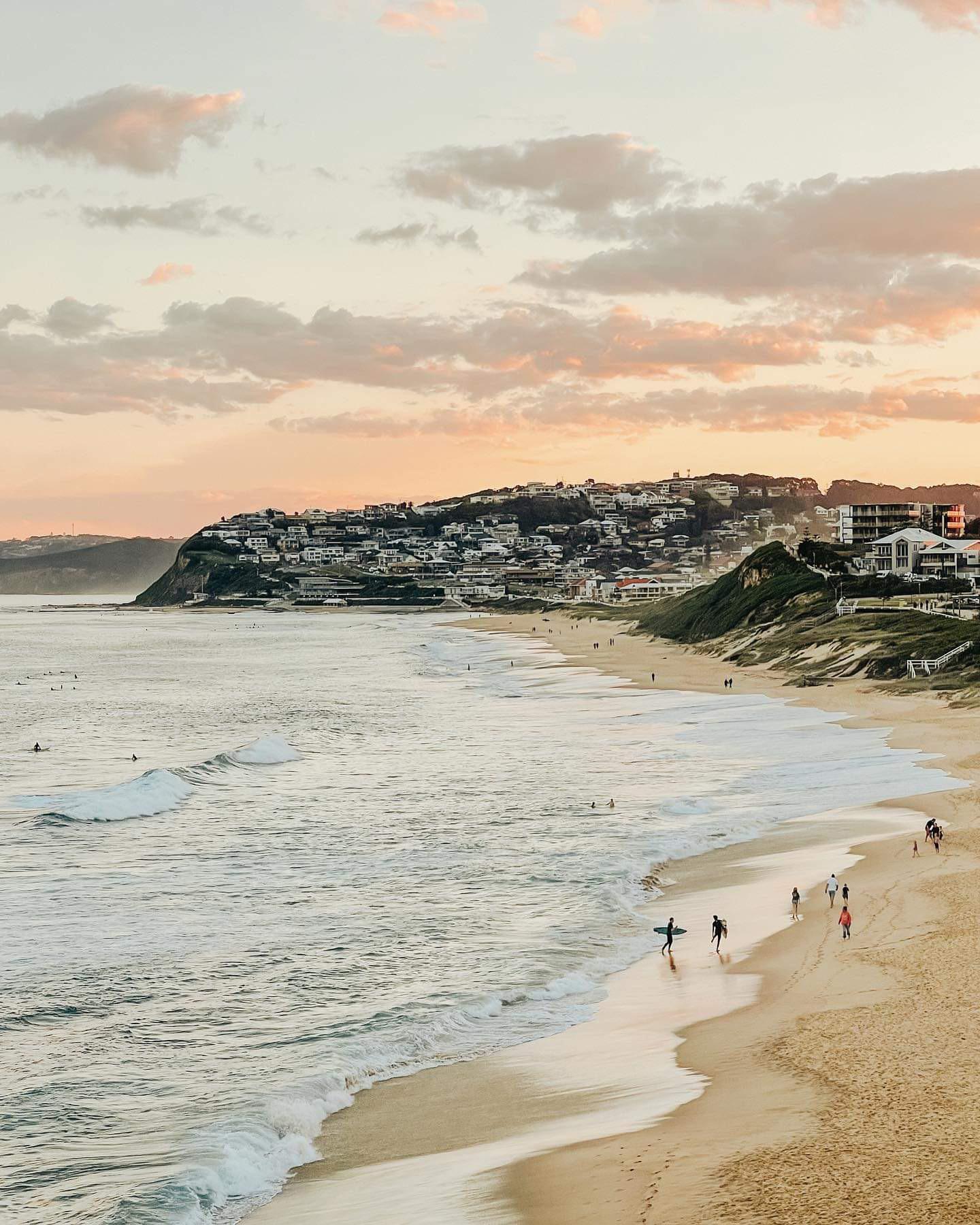 Merewether Beach at sunset, Newcastle, with homes stacked on the headland above the sand.