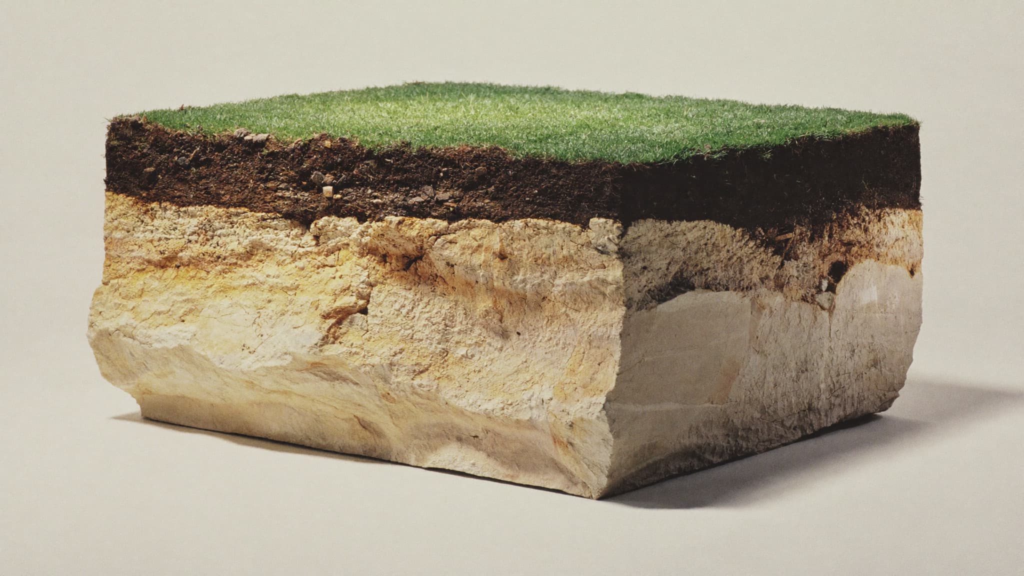 A cross-section of a square of Sydney ground: grass, dark topsoil, and pale golden Hawkesbury sandstone beneath.